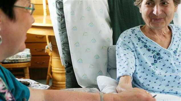 Une malade en fin de vie, tenue par la main par son médecin.