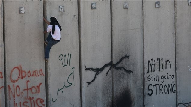 Un Palestinien escalade le mur (archives)