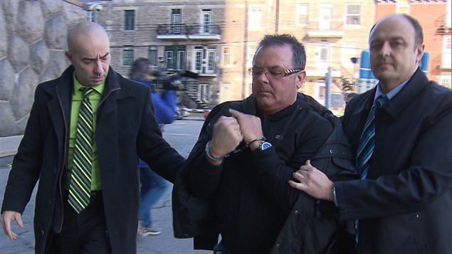 Raynald Desjardins escorté par les policiers après son arrestation.
