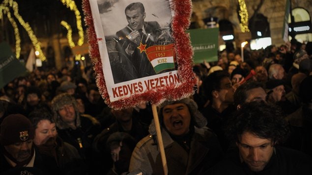 Des manifestants brandissent une pancarte représentant le premier ministre hongrois Viktor Orban en dictateur communiste, lundi, à Budapest.