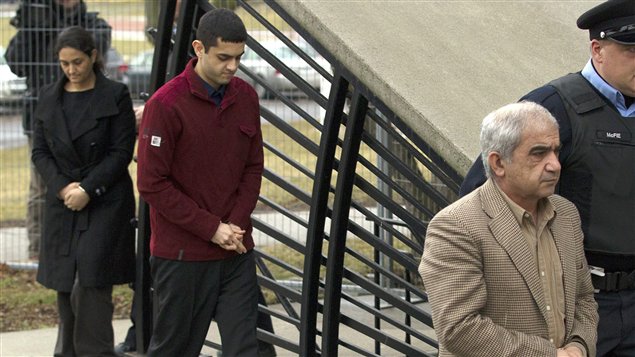 Mohammad Shafia est escorté par un policier au palais de justice de Kingston, suivi de son fils Hamed Mohammad et de sa seconde épouse, Tooba Yahya.