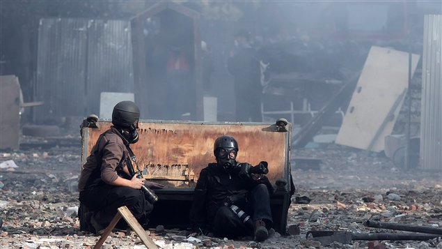 Des photographes étrangers se protègent des gaz lacrymogènes près de la place Tahrir, en Égypte, en novembre 2011.