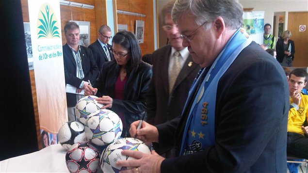 Le ministre responsable de l'Abitibi-Témiscamingue, Pierre Corbeil, signe des ballons de soccer