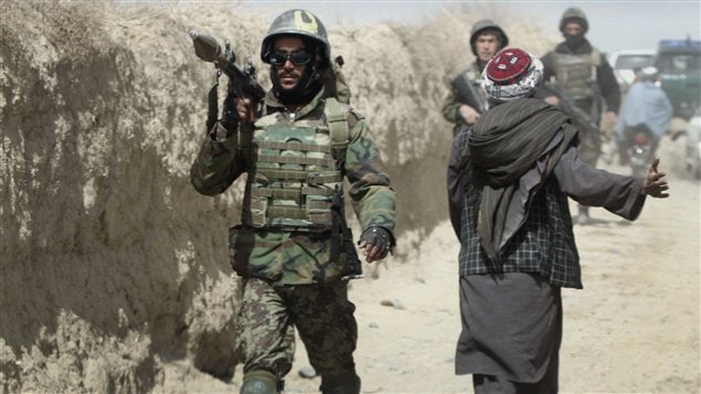 Un soldat afghan transporte un lance-grenades sur son épaule en marchant vers le site où les militants ont ouvert le feu sur une délégation de hauts responsables afghans à Panjwai, la province de Kandahar au sud de Kaboul, en Afghanistan.