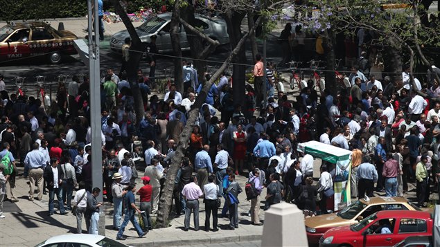 Des travailleurs et des résidents rassemblés au square de l'Ange de l'Indépendance, à Mexico, après avoir évacué des bâtiments.