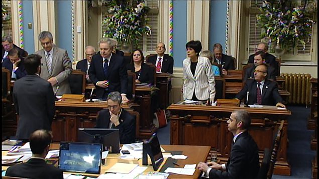 Le premier ministre Jean Charest se lève pour appuyer le principe du projet de loi spéciale déposé par son gouvernement. À gauche, le ministre de la Justice, Jean-Marc Fournier; à droite, la ministre de l'Éducation, Michelle Courchesne.
