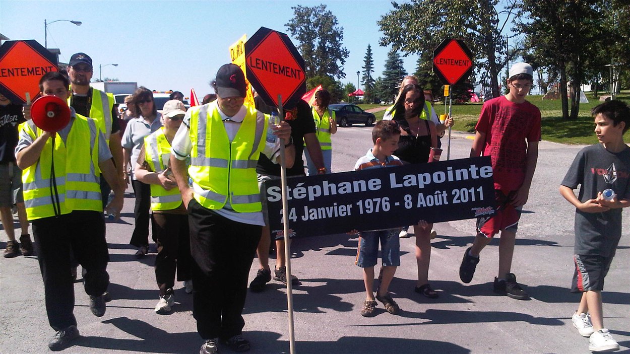 Une cinquantaine de personnes marchent dans les rues d'Amos pour rendre hommage au signaleur routier Stéphane Lapointe, qui a été happé par une voiture en 2011.