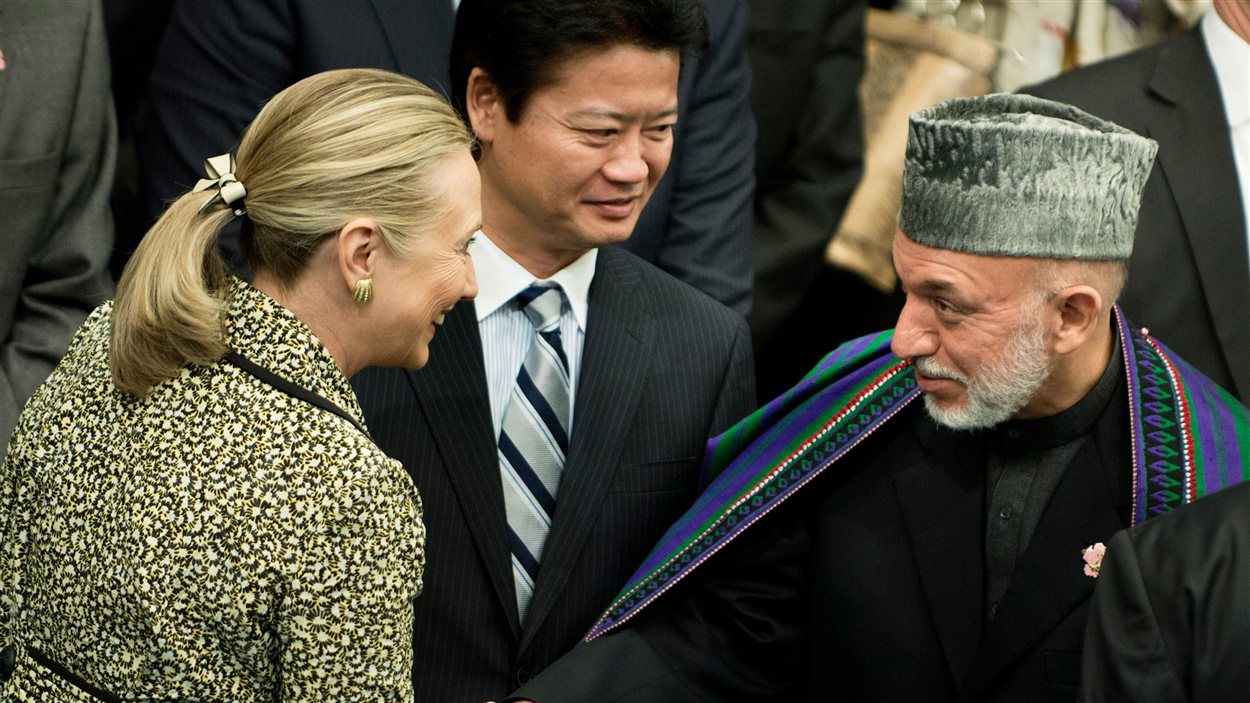 La secrétaire d'État américaine, Hillary Clinton, serre la main du président afghan, Hamid Karzaï, sous le regard du ministre japonais des Affaires étrangères, Koichiro Gemba, le 8 juillet, à Tokyo.