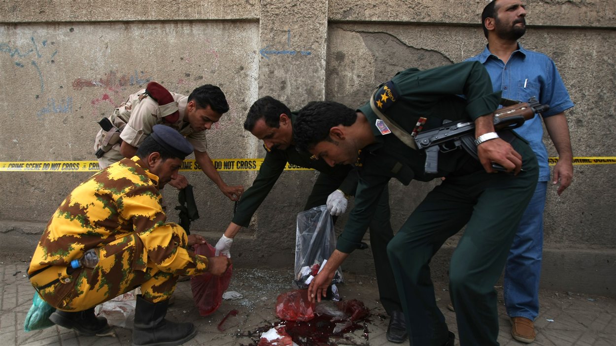 Des policiers et militaires yéménites récoltent des indices sur le lieu d'un attentat suicide, à Sanaa.