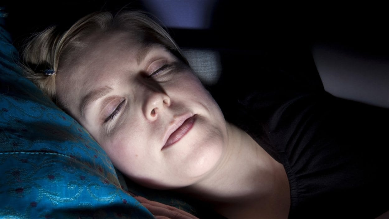Une femme dort devant la télévision.