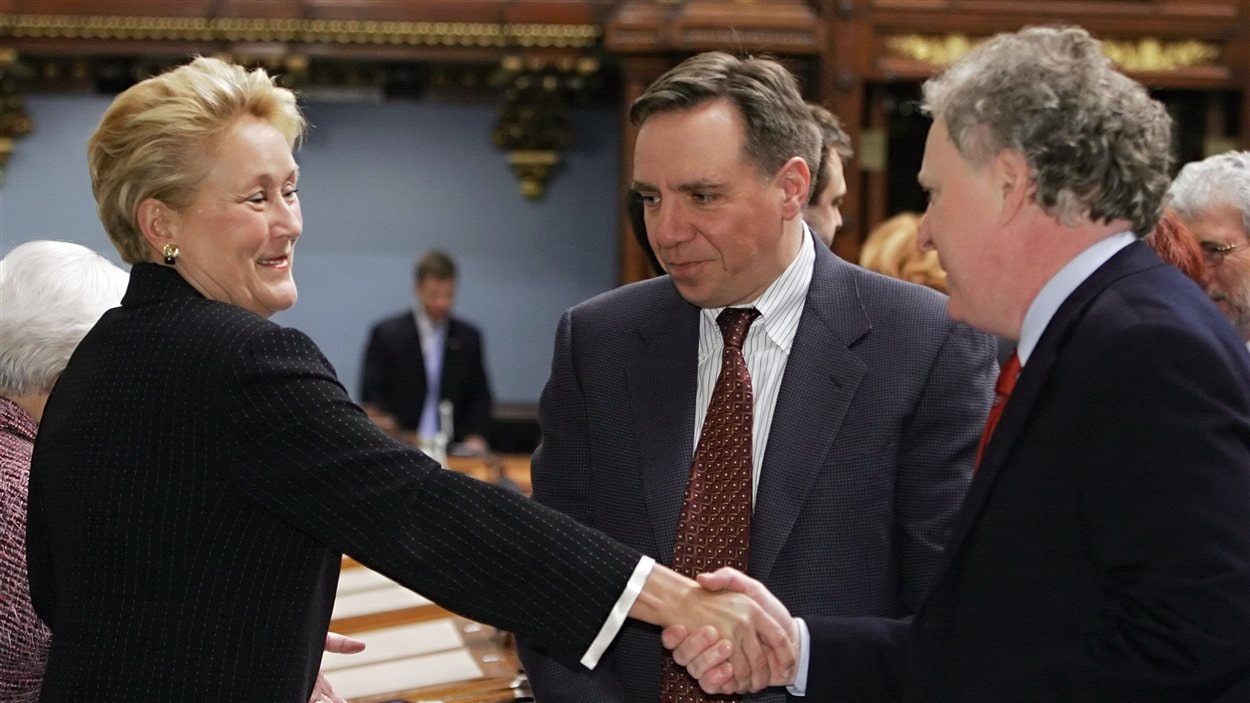 Le premier ministre Jean Charest serre la main de la députée Pauline Marois quelques minutes avant l'annonce de sa démission. Entre les deux, on peut voir François Legault, alors député péquiste. (2006)