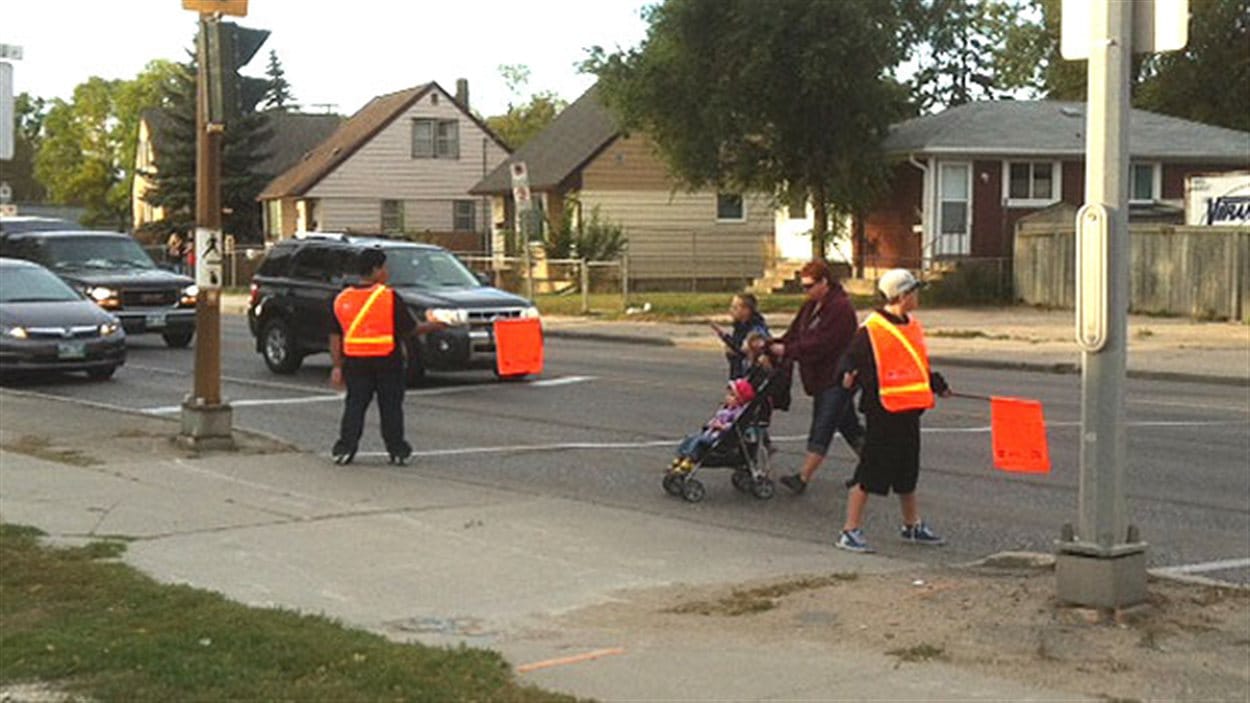 Des patrouilleurs de quartier aident les piétons à traverser la route jeudi près de l'École Archwood à Winnipeg.