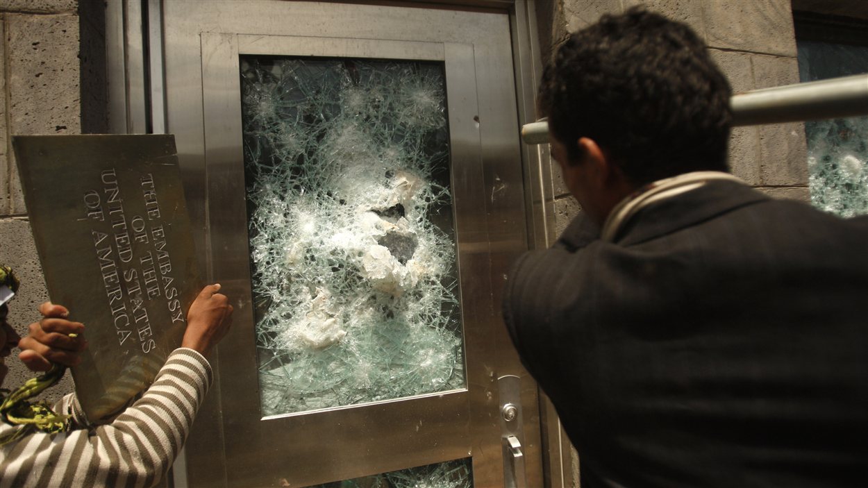 Au Yémen, un protestataire tente de fracasser la porte de l'ambassade américaine à Sanaa.