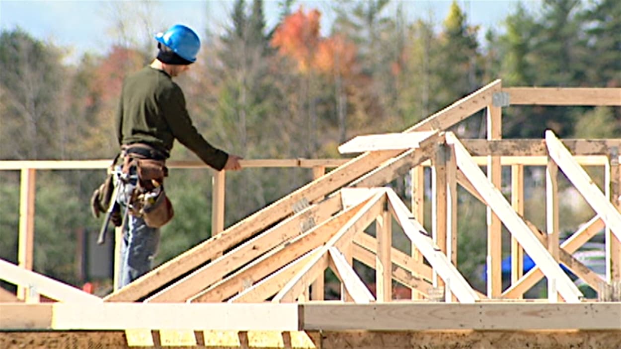 Un employé de la construction travaille sur le toit d'une résidence à Gatineau.