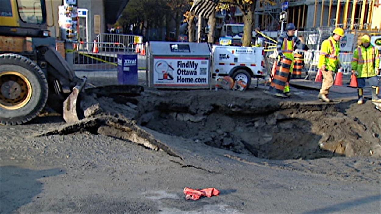 Les employés de la voierie travaillent à réparer l'important bris d'une conduite d'eau sur la rue Elgin, à Ottawa.