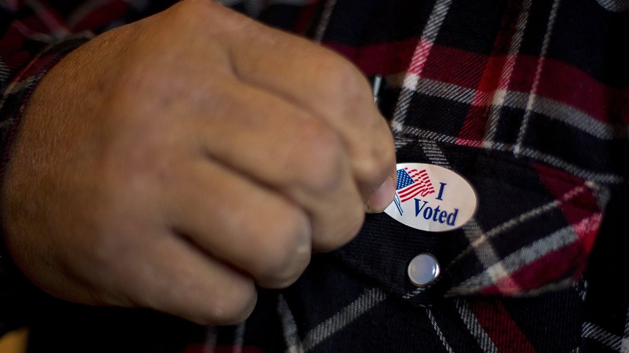 Un homme posant un autocollant « I Voted » sur sa chemise après avoir mis le bulletin dans l'urne à Otter Creek dans l'Iowa.