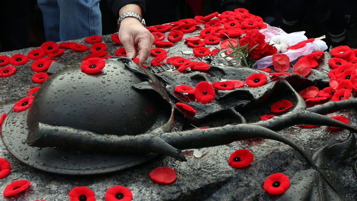 Des Canadiens déposent leur coquelicot sur la tombe du soldat inconnu à Ottawa.