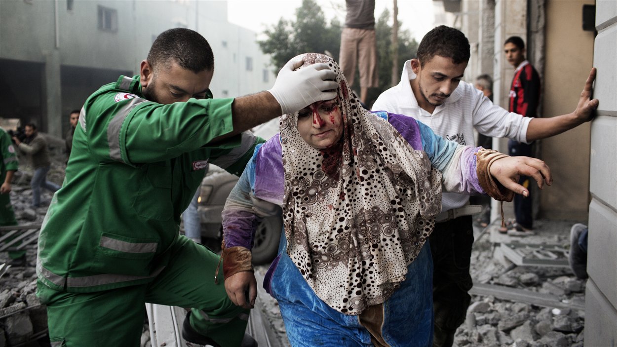 Une Palestinienne reçoit de l'aide d'un ambulancier pour sortir d'un immeuble visé par les raids israéliens dans le centre de la ville de Gaza le 19 novembre. 