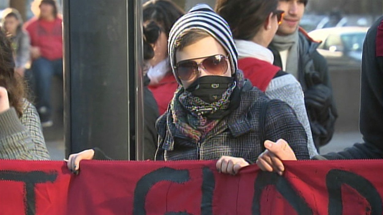 Un manifestant tenant avec ses pairs une bannière sur laquelle on peut lire : « La crise est globale, la lutte est mondiale, résistance générale. »
