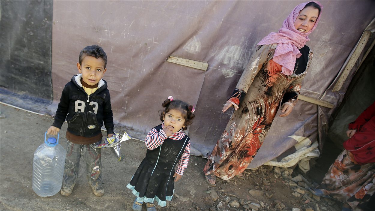 Des réfugiés syriens attendent à côté de leurs abris de fortune dans un champ de Saadnayel, dans la vallée de la Bekaa, au Liban, le 12 décembre 2012.