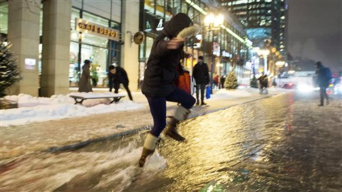 Une femme traverse la rue inondée à Montréal.