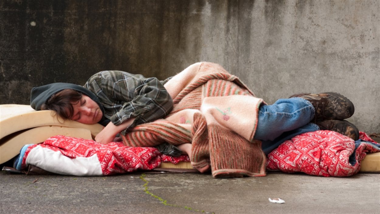 Une sans-abris dort par terre.
