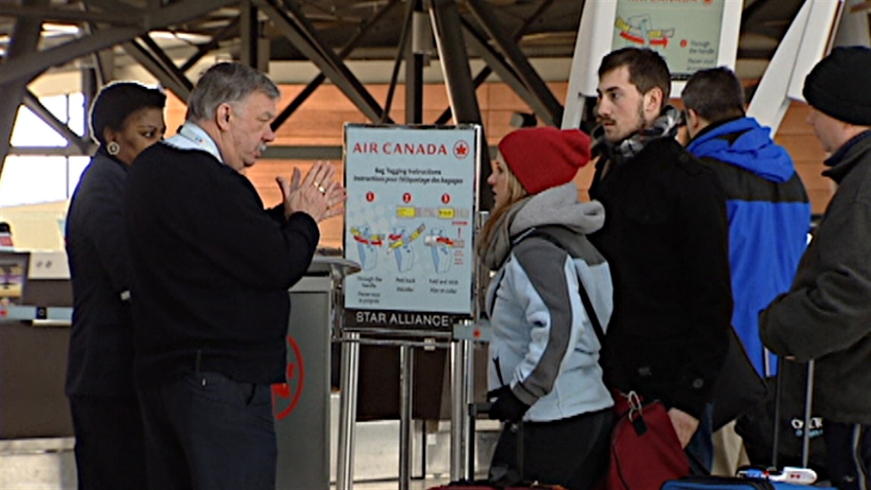 Des clients à l'aéroport d'Ottawa attendent au guichet d'Air Canada.