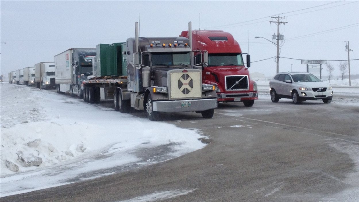 Environ deux douzaines de semi-remorques attendent la réouverture de l'autoroute Transcanadienne à l'ouest de Winnipeg, le 18 février 2013.