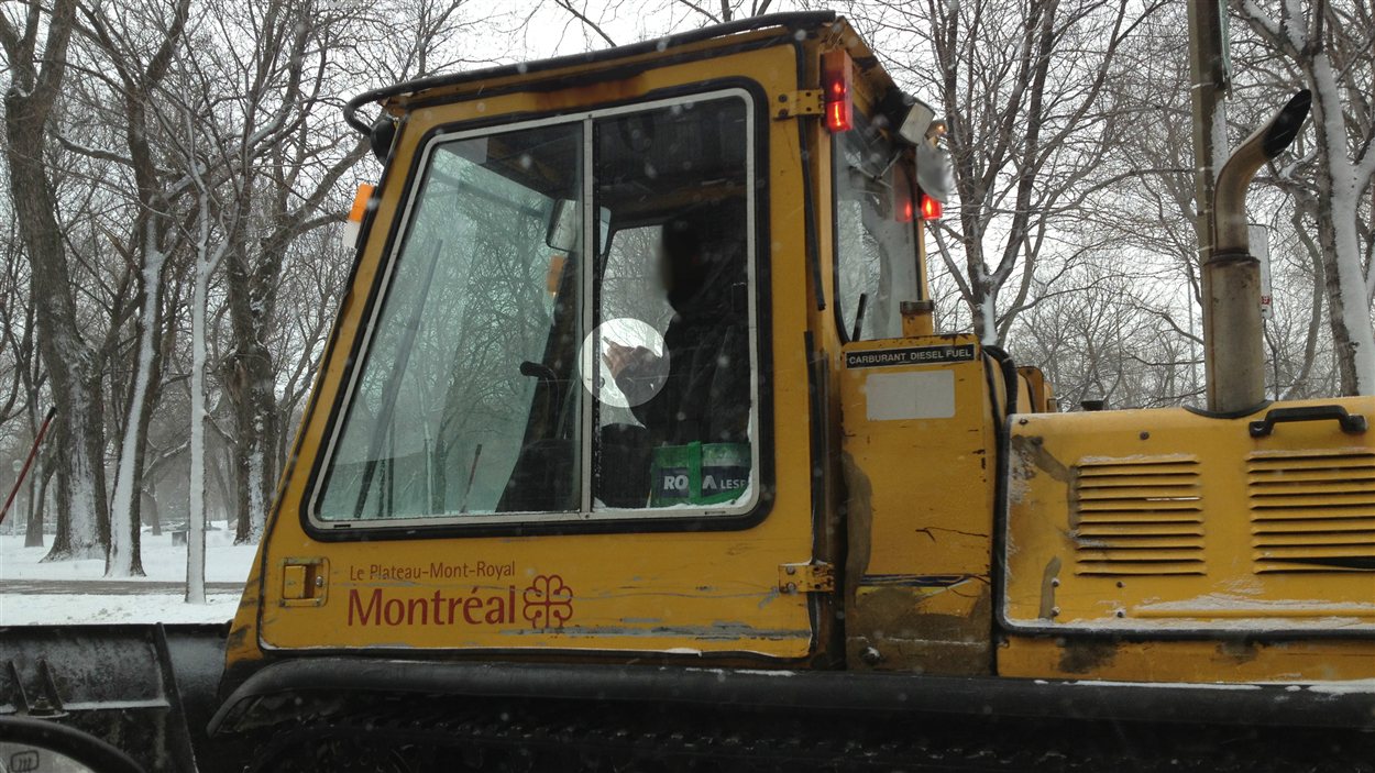 Un employé de la Ville de Montréal les yeux rivés sur son téléphone pendant qu'il circule sur la chaussée.