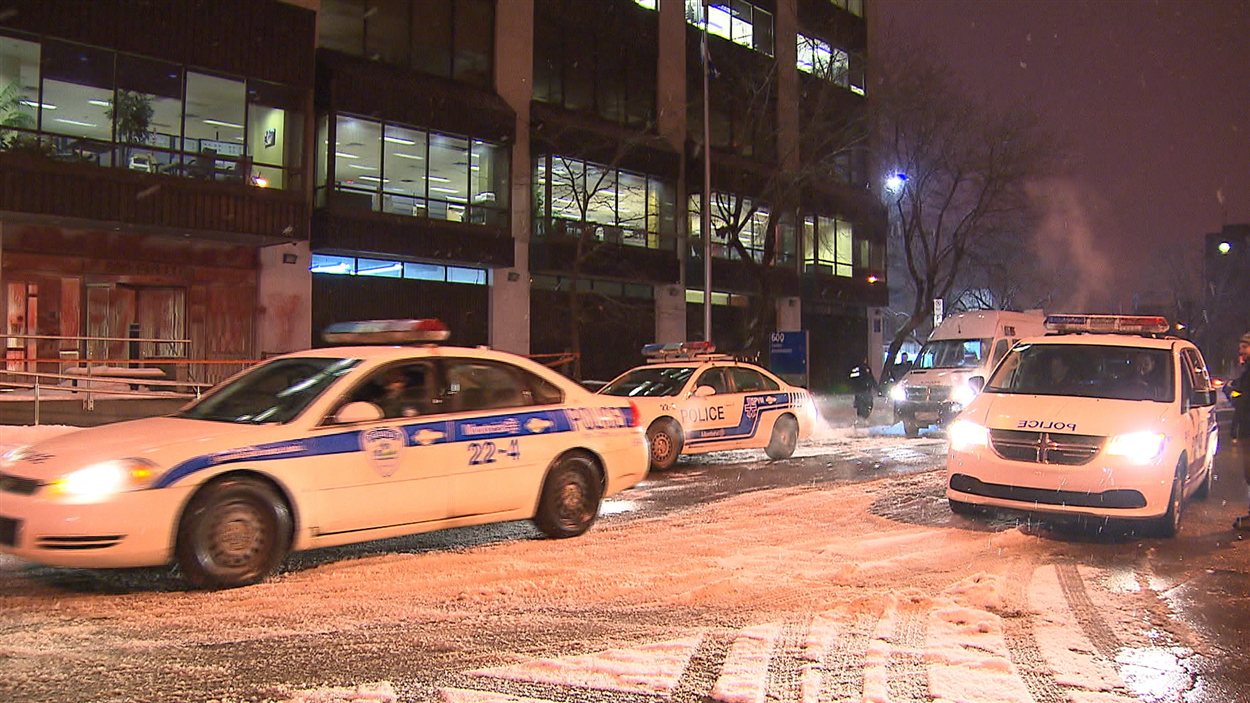 Des voitures de police arrivent devant les locaux du ministère de l'Éducation, à Montréal, où l'entrée a été aspergée de peinture rouge.