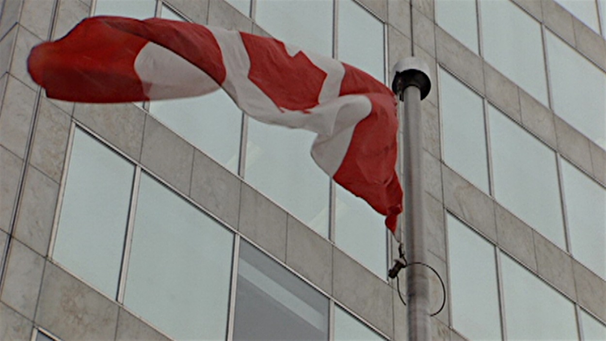 Un drapeau canadien flotte devant un édifice fédéral à Ottawa.
