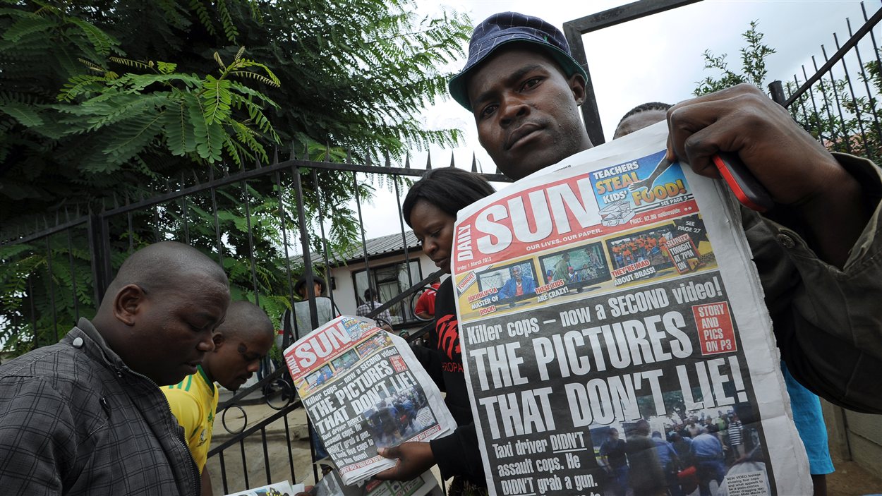 Des proches de Mido Macia brandissent la Une de la presse locale, qui revient sur des images qui ont fait le tour du monde.