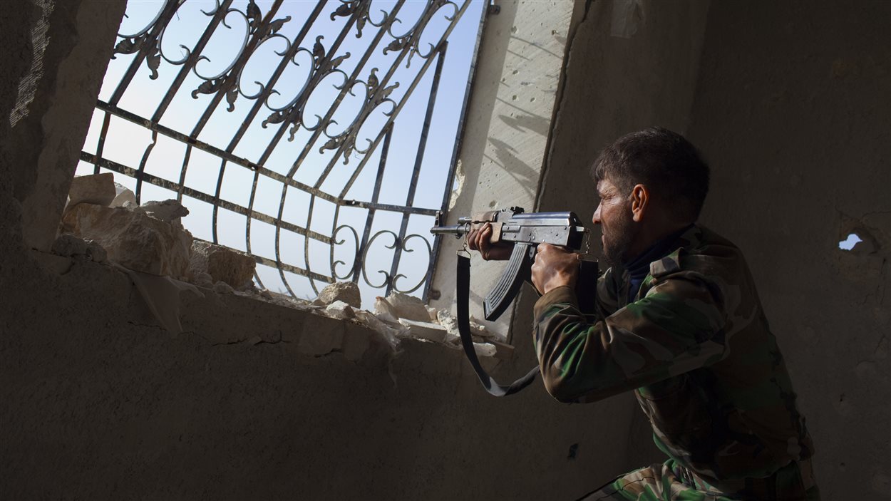 Un rebelle syrien pointe son arme vers les forces gouvernementales près d'Alep, le mars 2013. 