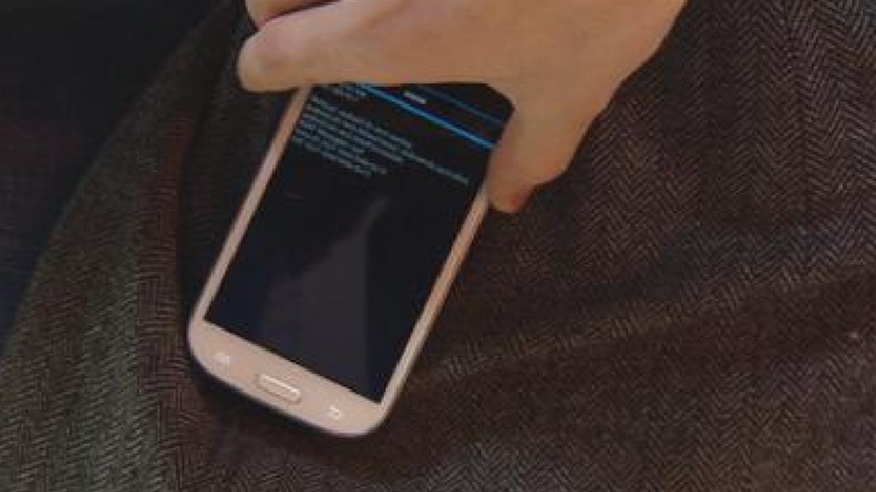 Une application sur un téléphone intelligent déchiffre les informations d'une carte de crédit insérée dans la poche d'un manteau.