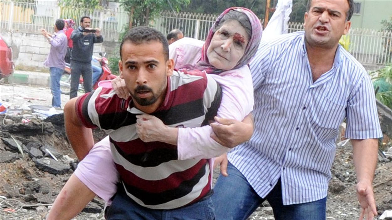 Des résidents de Rayhanli, en Turquie, évacuent une femme blessée après l'explosion d'une voiture, le 11 mai 2013
