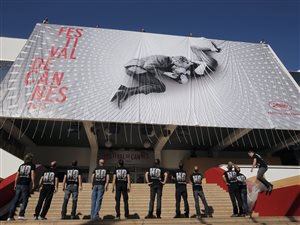 Des travailleurs regardent l'affiche officielle du Festival de Cannes.