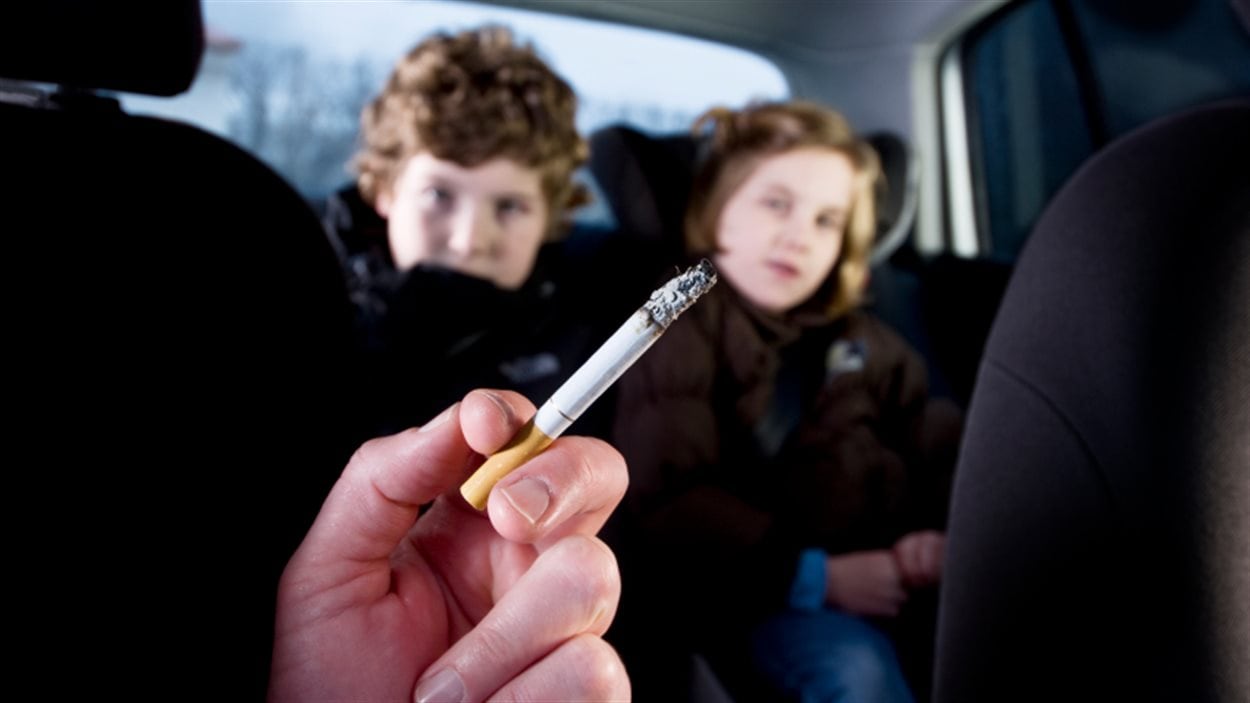 Un passager d'une voiture fume en présence d'enfants