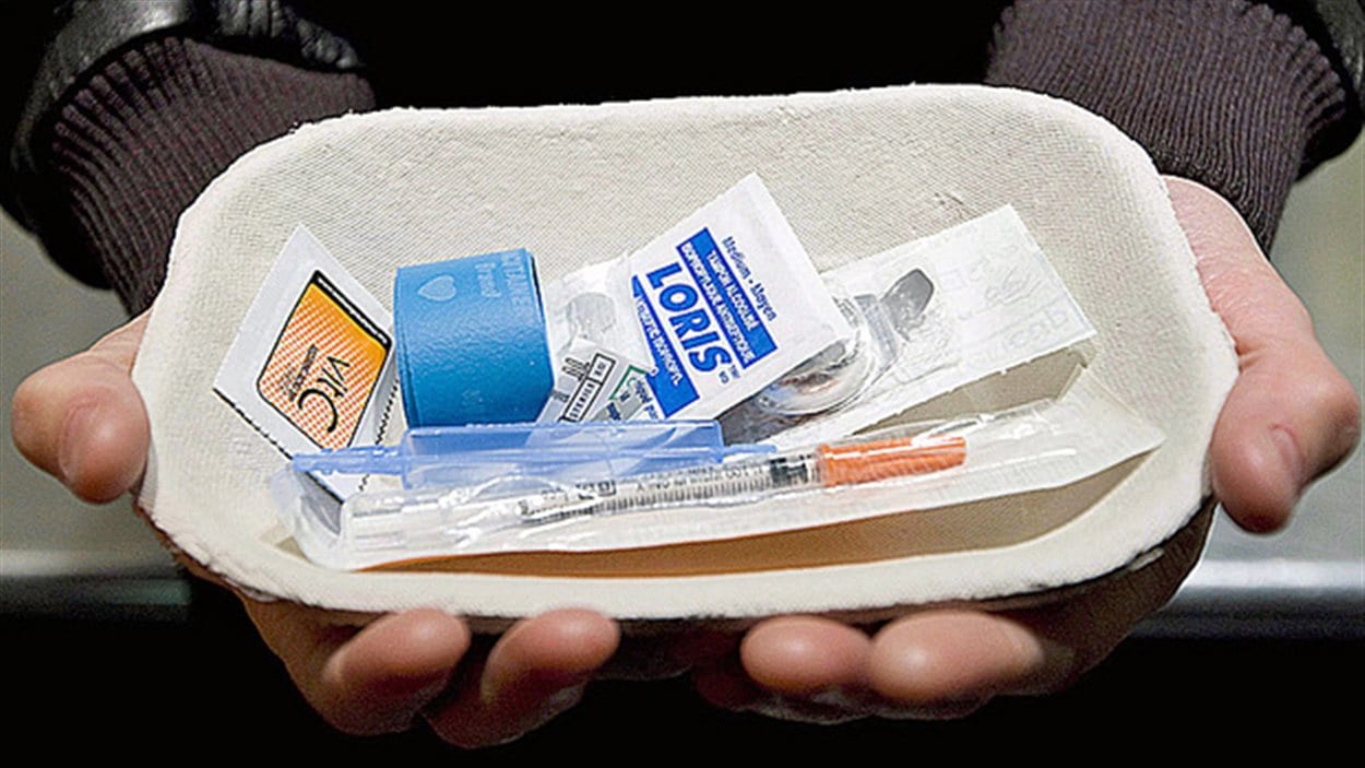 Un homme tient un nécessaire à injection supervisée de drogue.