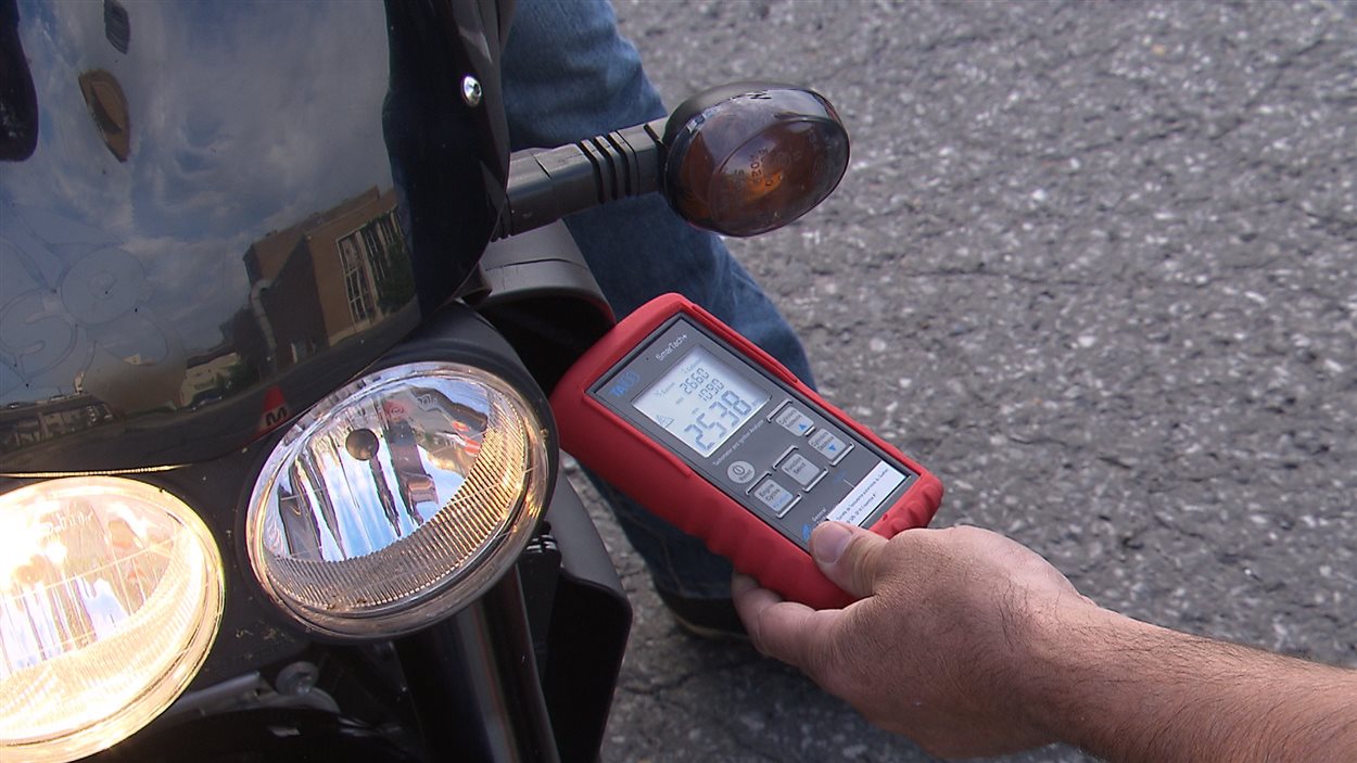 Un policier mesure le niveau du bruit émis par une motocyclette à l'aide d'un sonomètre.