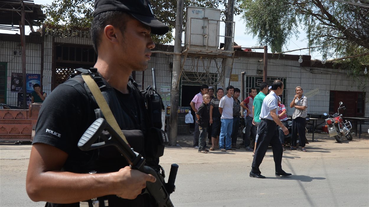 Un policier surveille la route empruntée mercredi par les émeutiers dans la ville de Lukqun, au Xinjiang.