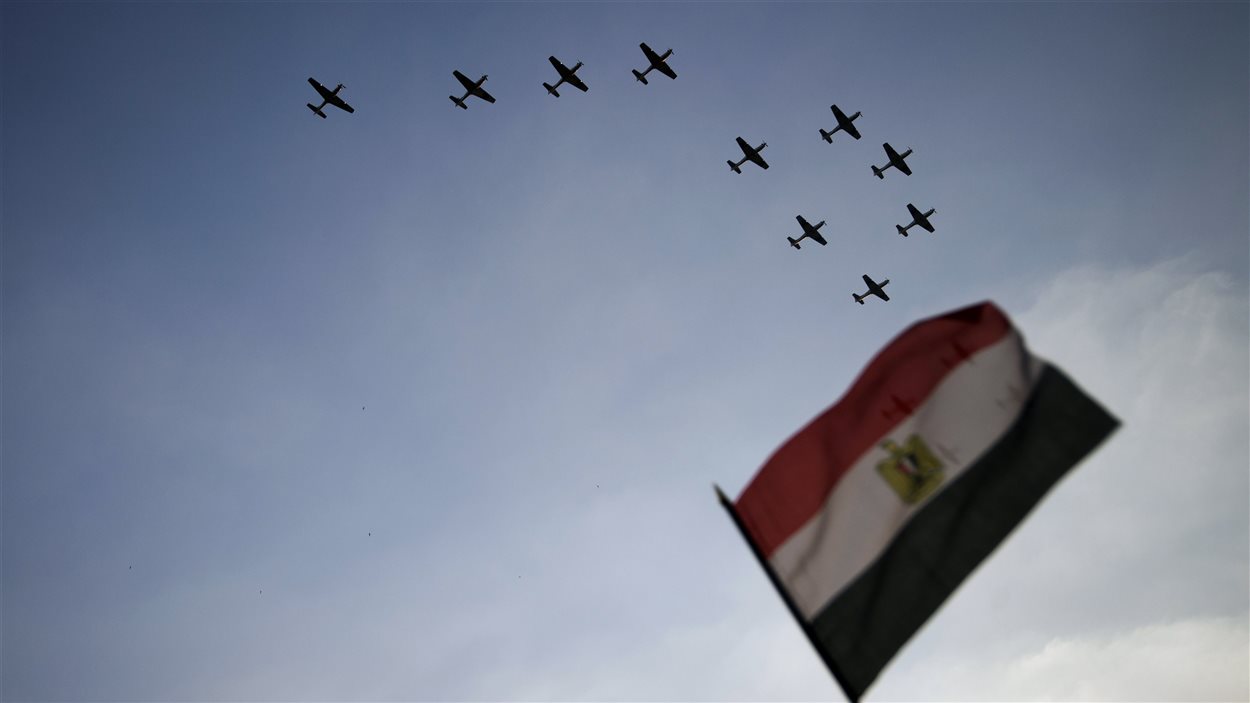Un drapeau égyptien en avant plan et des avions de l'armée dans le ciel