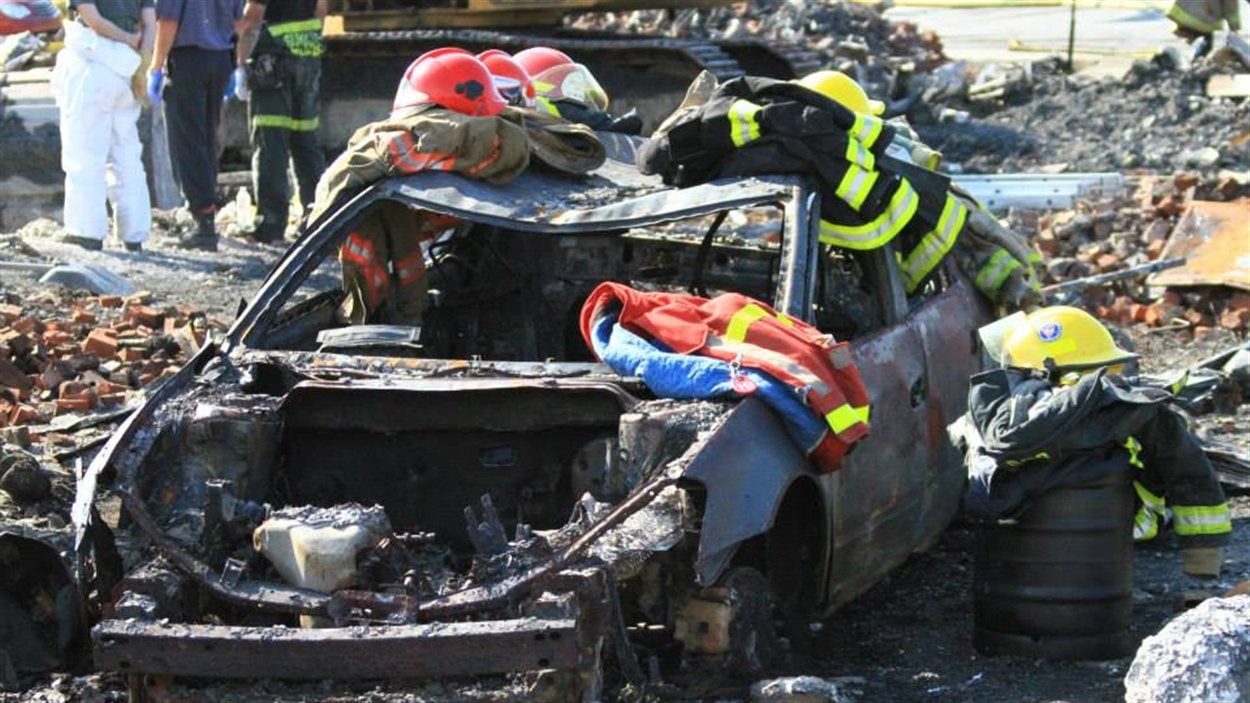 Des pompiers ont déposé leurs habits sur une voiture complètement carbonisée.