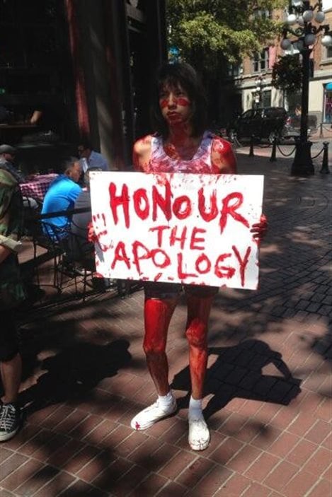 Une participante à l'événement Honour the Apology à Vancouver manifeste couverte de rouge, le 25 juillet 2013.