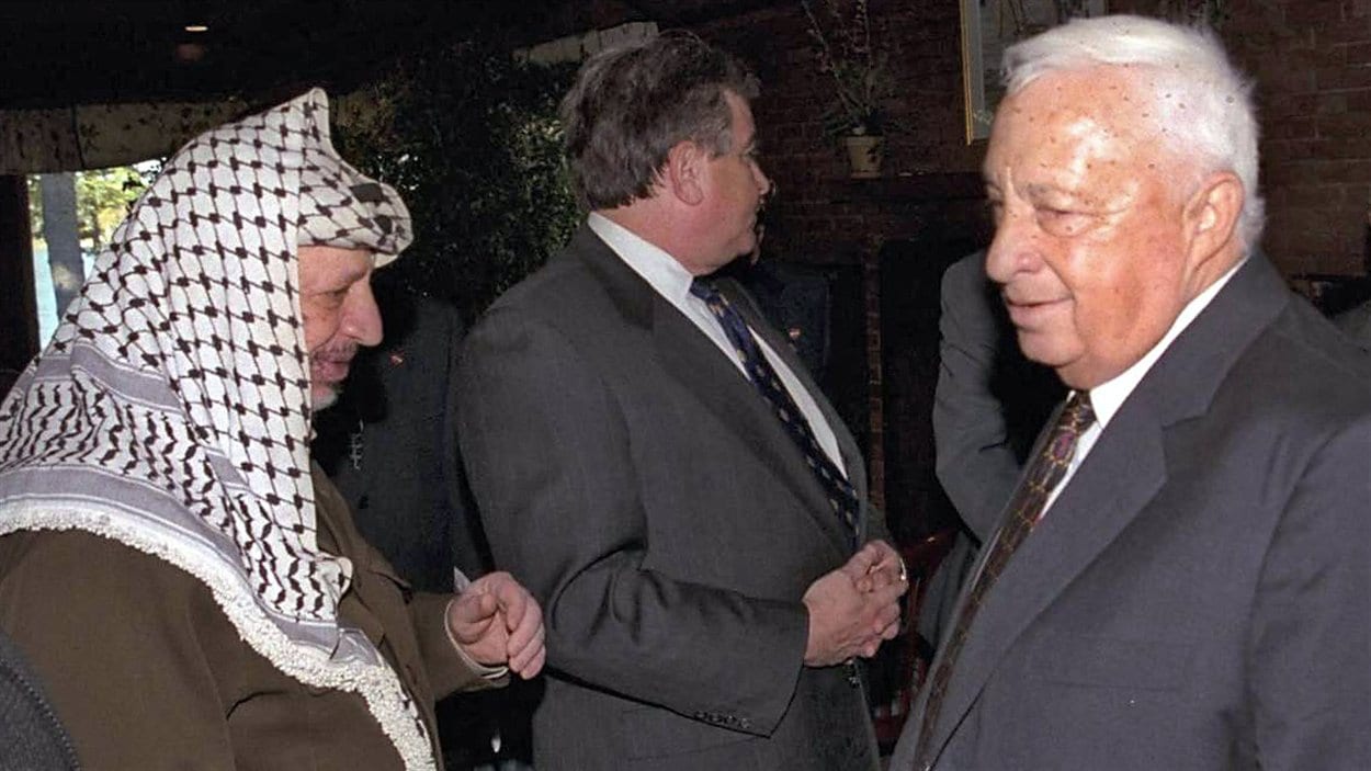 (21 octobre 1998) Ariel Sharon en compagnie du leader palestinien Yasser Arafat durant la reprise des négociations du processus de paix, à Wye Plantation, dans l’État du Maryland. 