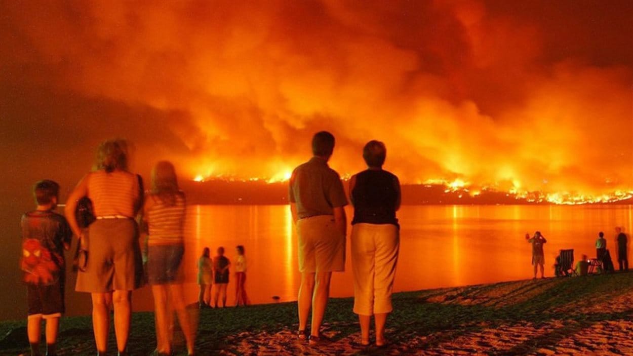 Des gens se sont rassemblés près de Kelowna pour regarder les flammes de l'autre côté du lac Okanagan, le 21 août 2003.