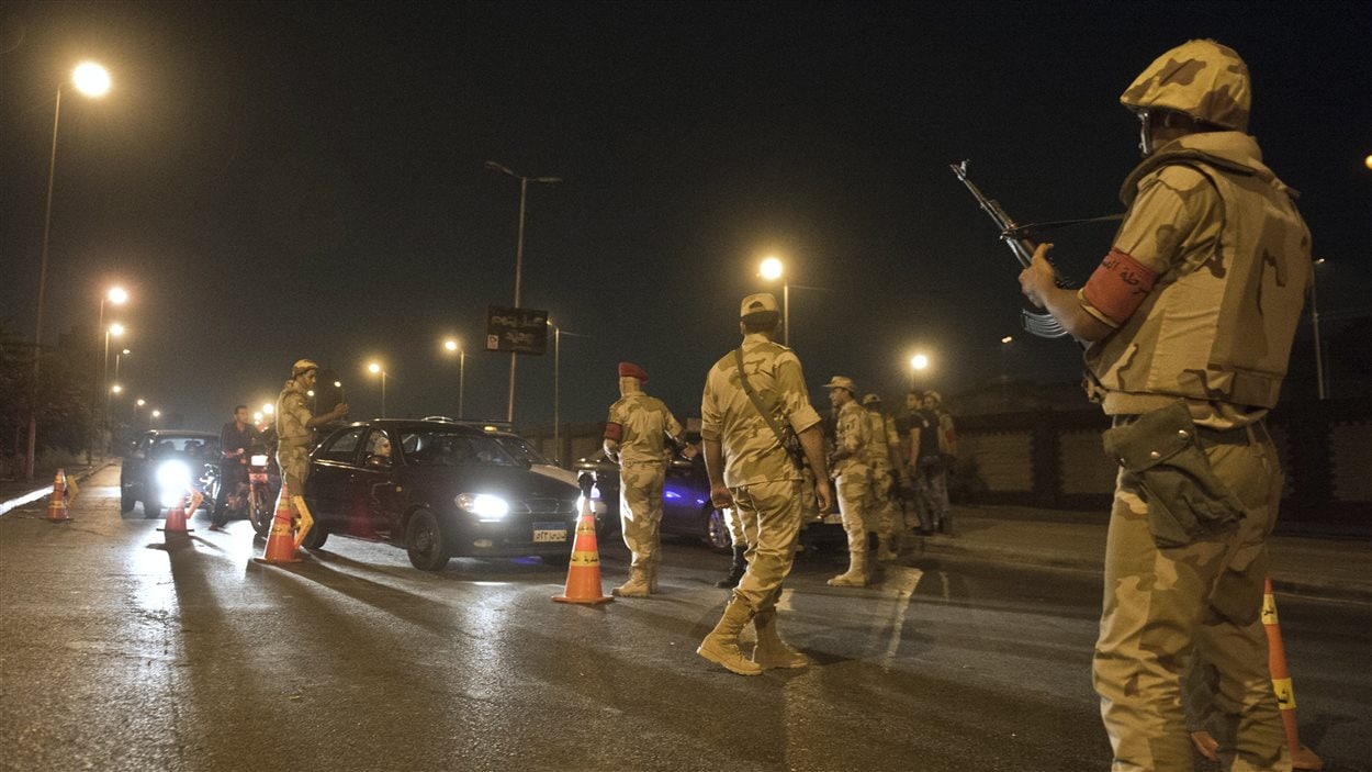 Des militaires contrôlent des voitures après le début du couvre-feu au Caire