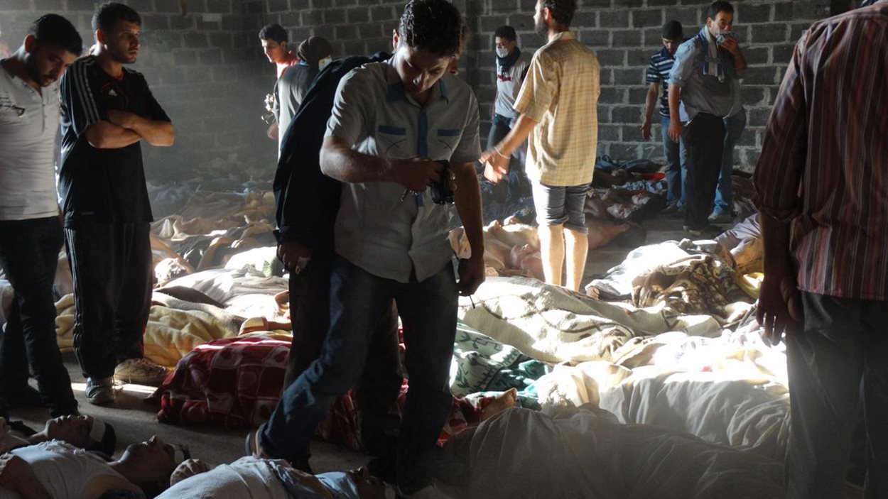 Image fournie par un groupe d'opposition syrienne qui montrerait des gens inspectant les corps de victimes de l'attaque au gaz neurotoxique dans des quartiers situés en périphérie de Damas, le 21 août.