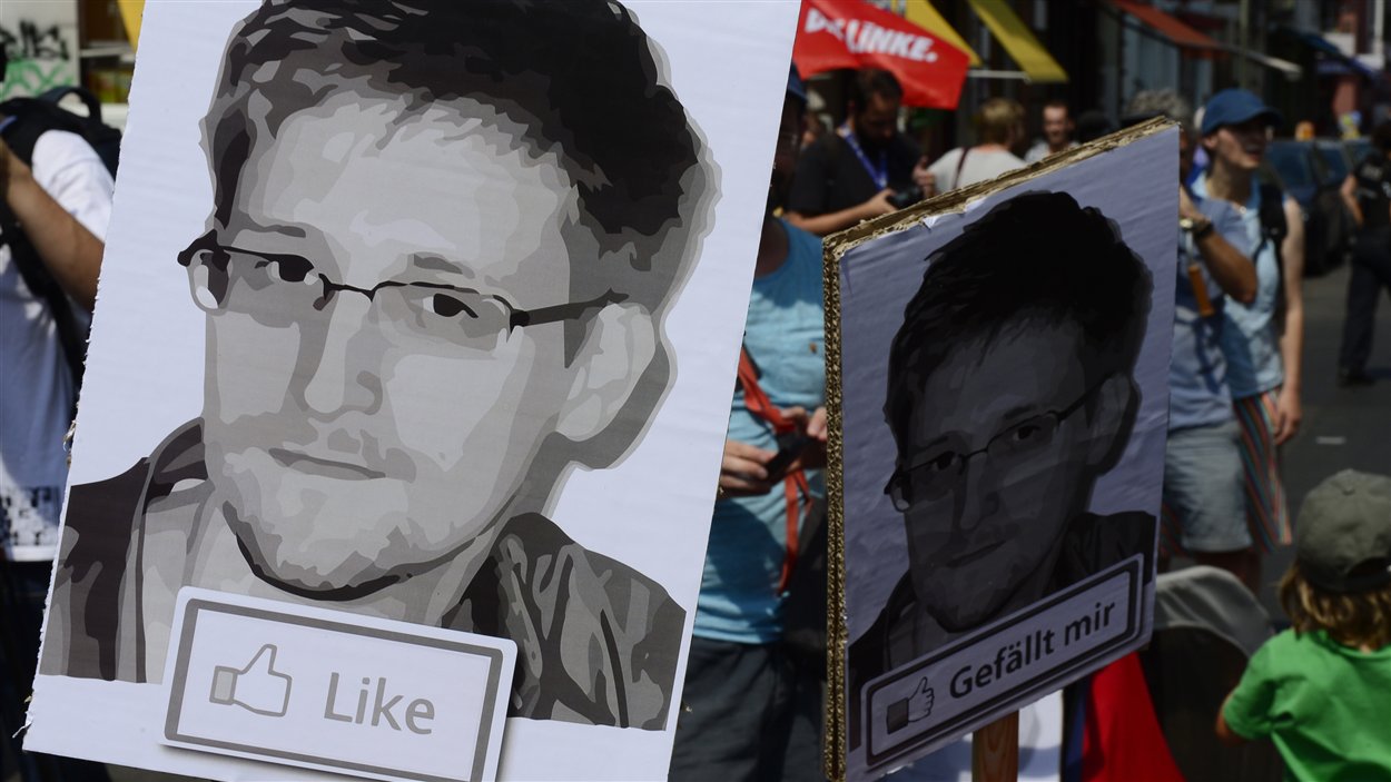 Des protestataires tiennent des affiches d'Edward Snowden à Berlin, en Allemagne, lors d'une manifestation contre les actes de la NSA.