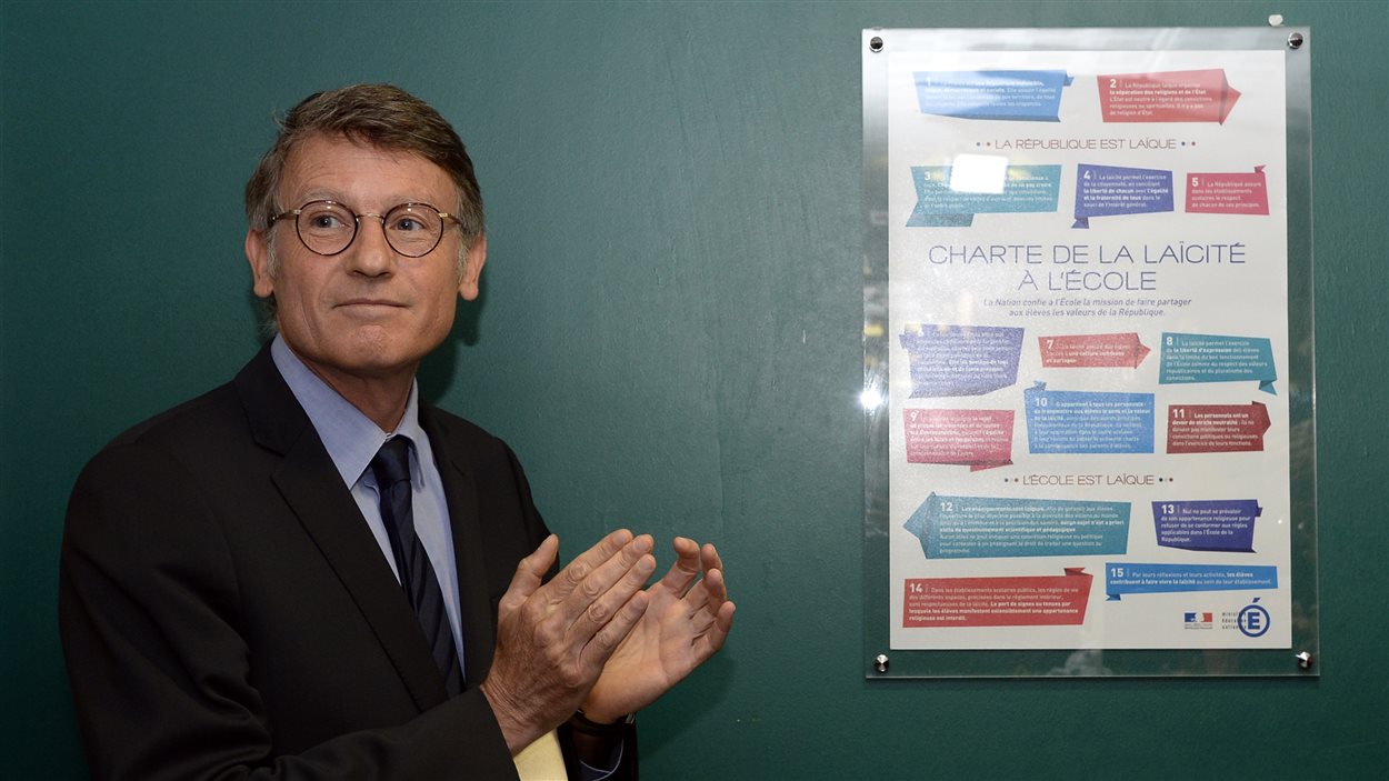 Le ministre de l'Éducation français, Vincent Peillon, devant l'affiche rappelant aux élèves les règles de laïcité en vigueur dans leur école.