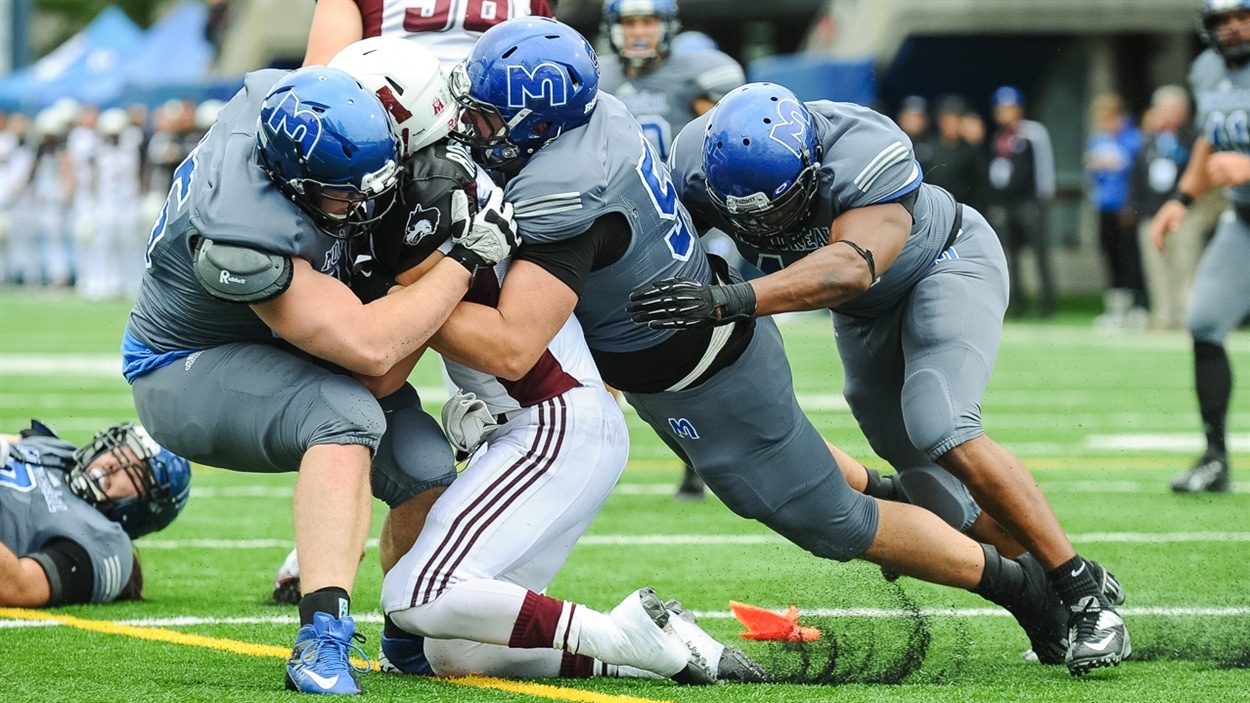 Les Carabins de l'Université de Montréal freinent le quart des Huskies de l'Université Saint Mary's.